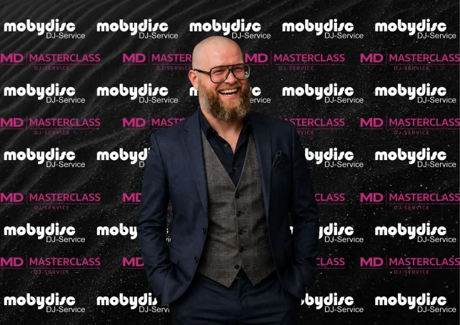 Professioneller Mobydisc DJ im eleganten Business-Outfit vor gebrandeter Eventwand