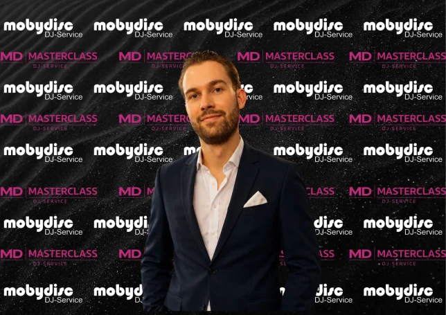 Eleganter Mobydisc DJ im modernen Sakko vor stilvoller Eventkulisse