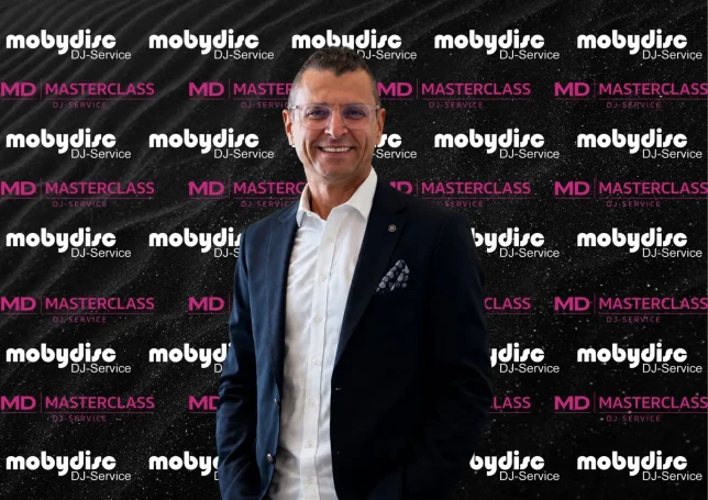 Eleganter Mobydisc Event-DJ im modernen Business-Look vor Event-Hintergrund