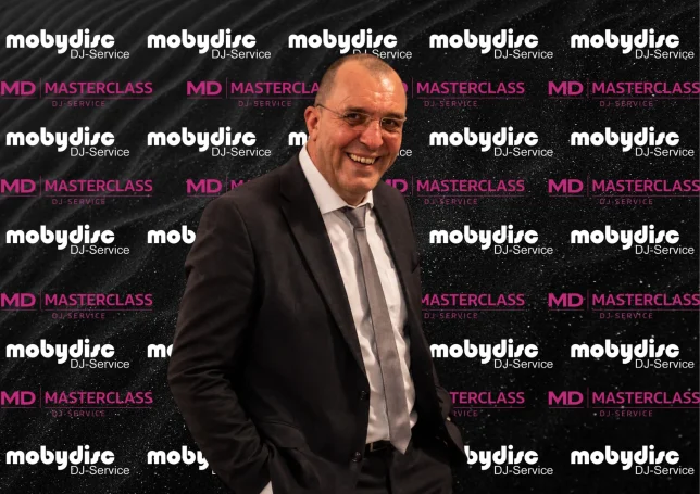 Erfahrener Mobydisc DJ im Anzug vor professioneller Mobydisc Eventwand